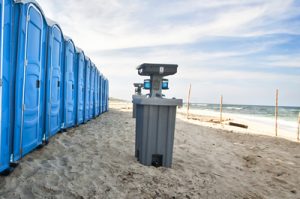 portable toilets on a beach with a hand washing station